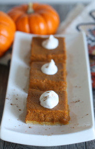 Plate of three pumpkin squares with pumpkins in the background.